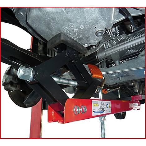 Ein schwarzer Wagenheber stützt ein Fahrzeug von unten ab. Darunterliegend rot-silberne Metallteile.